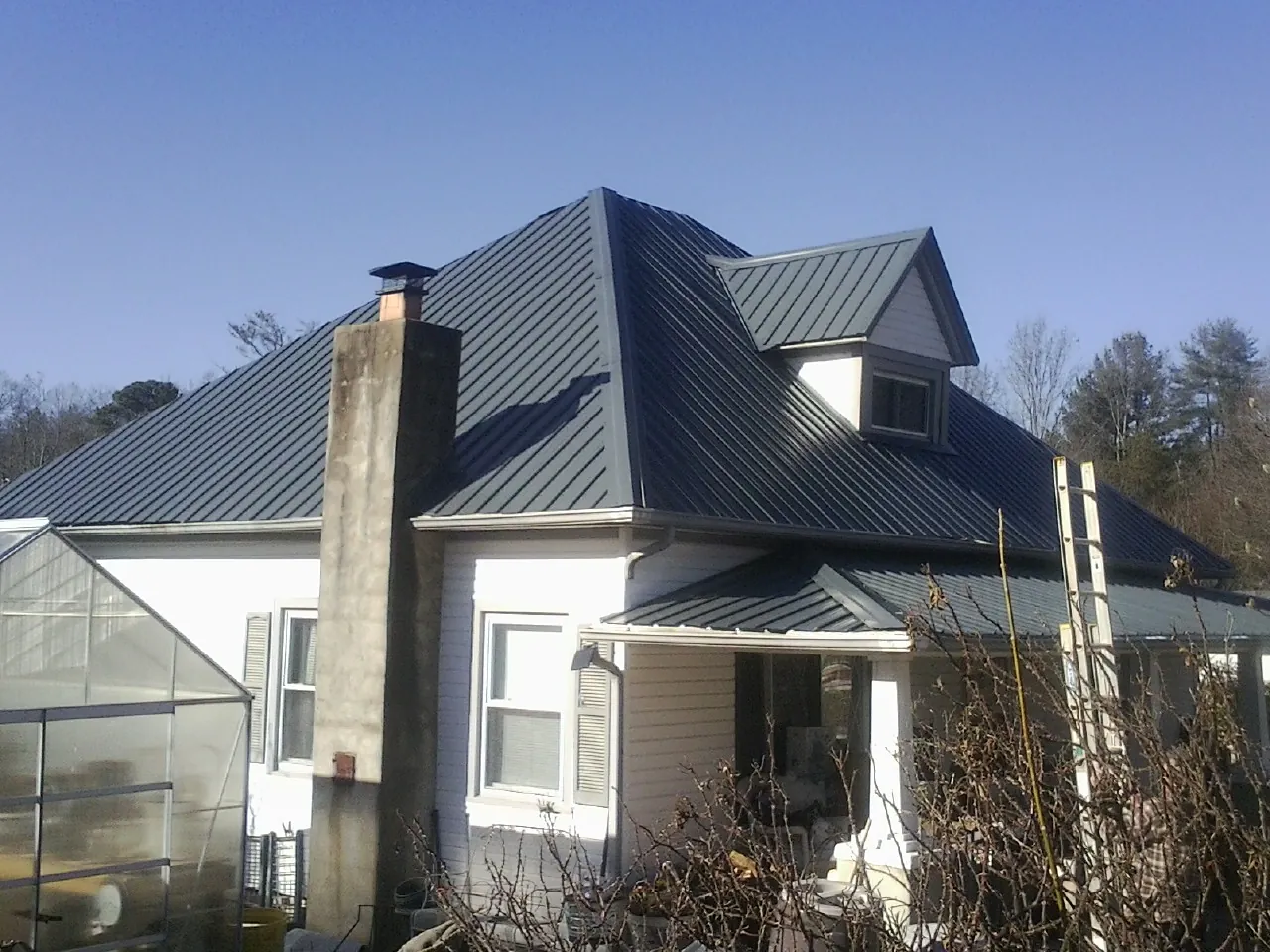 Dark blue standing seam metal roof on a white farmhouse with dormer — Slate & Tile Roof Repair by Roofing Brothers in Seal Rock
