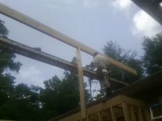 Carpenter setting a ridge beam over a new addition frame — Ice Dam Removal by Roofing Brothers in Seal Rock