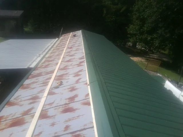Old rusted panels beside newly installed green metal roofing — Wind Damage Roof Repair by Roofing Brothers in Seal Rock