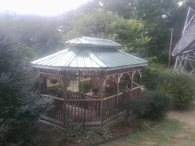 Green metal roof on a backyard gazebo surrounded by garden beds in Seal Rock