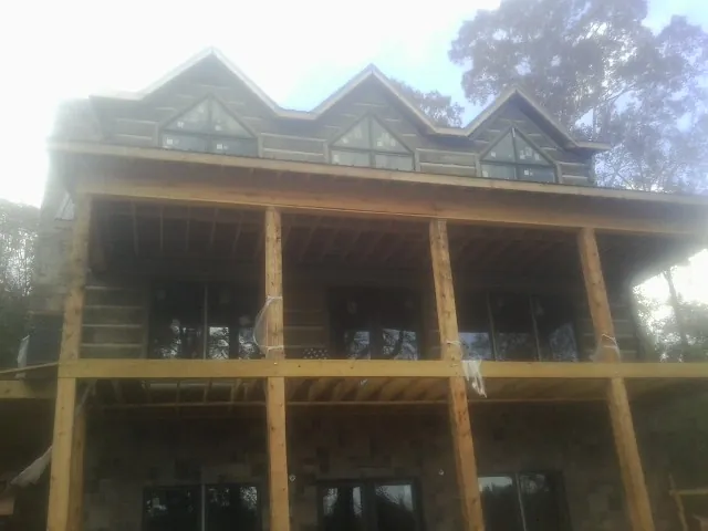 Dormers and porch framing on a large log home under construction — Roof Coating work by our crew in Seal Rock