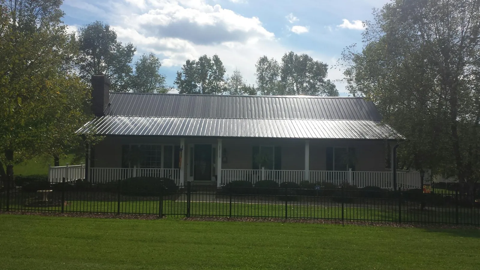 Gray metal roof on a brick ranch with a full width front porch — Gutter Guard Installation work by our crew in Seal Rock