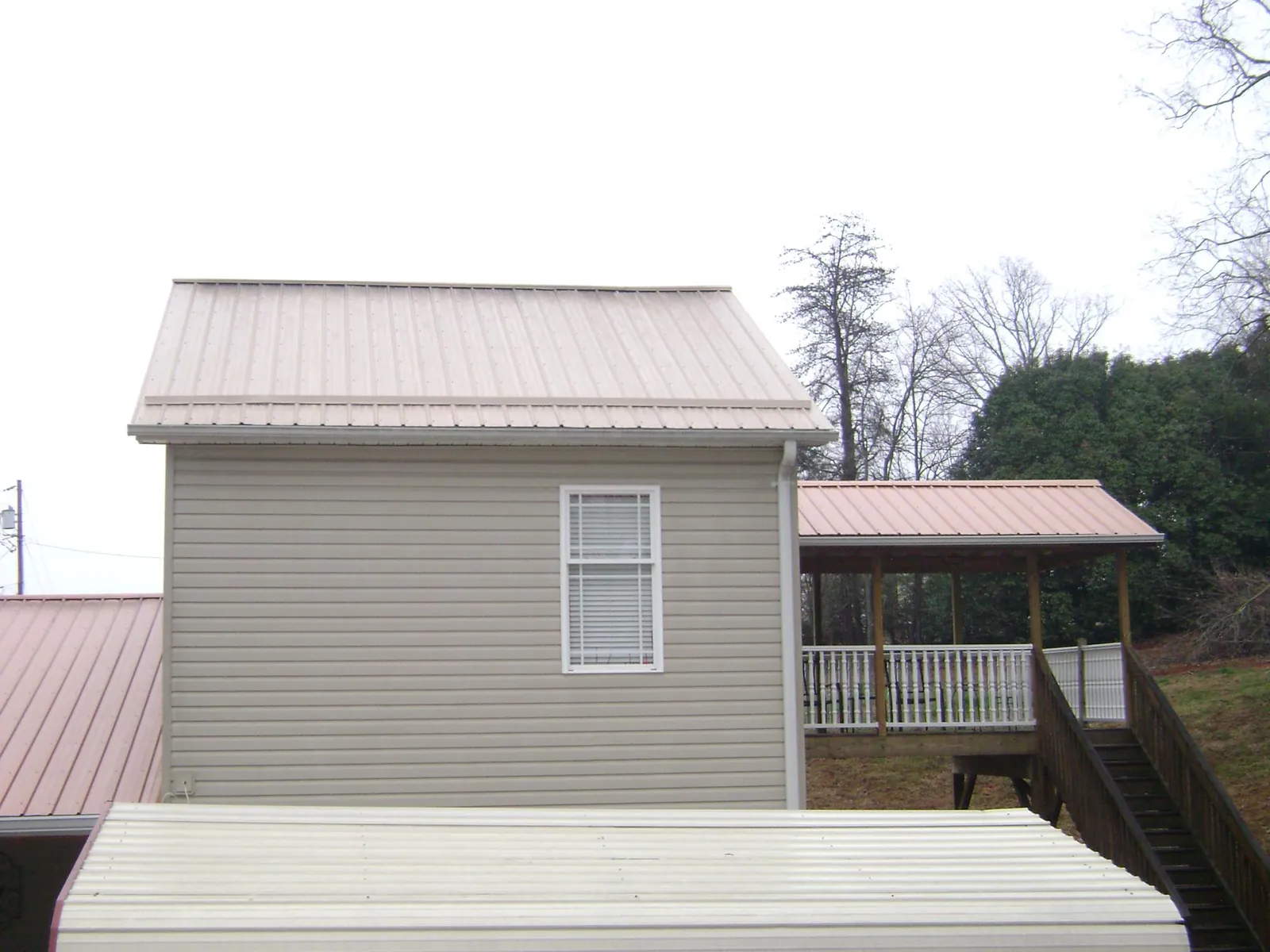 Tan metal roofs on a two story addition and attached porch, from a Roof Replacement job in Seal Rock