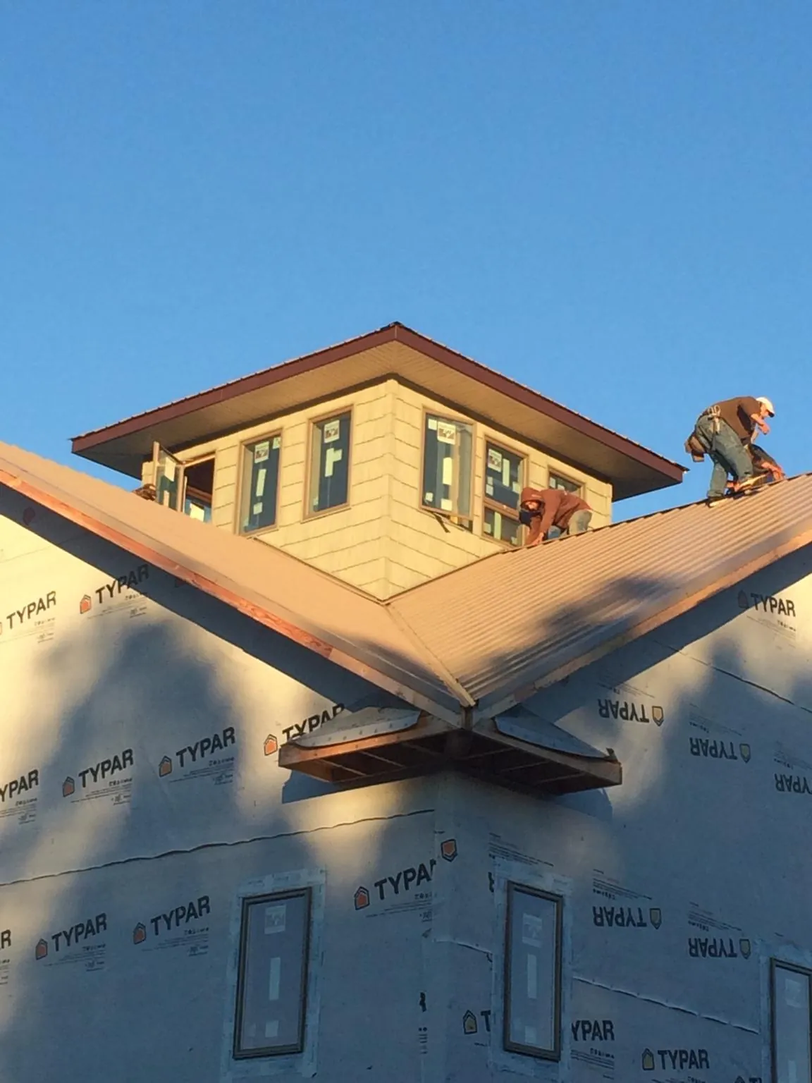 Roofers working around a rooftop cupola on a new metal roof at sunset — Roof Waterproofing in Seal Rock by Roofing Brothers
